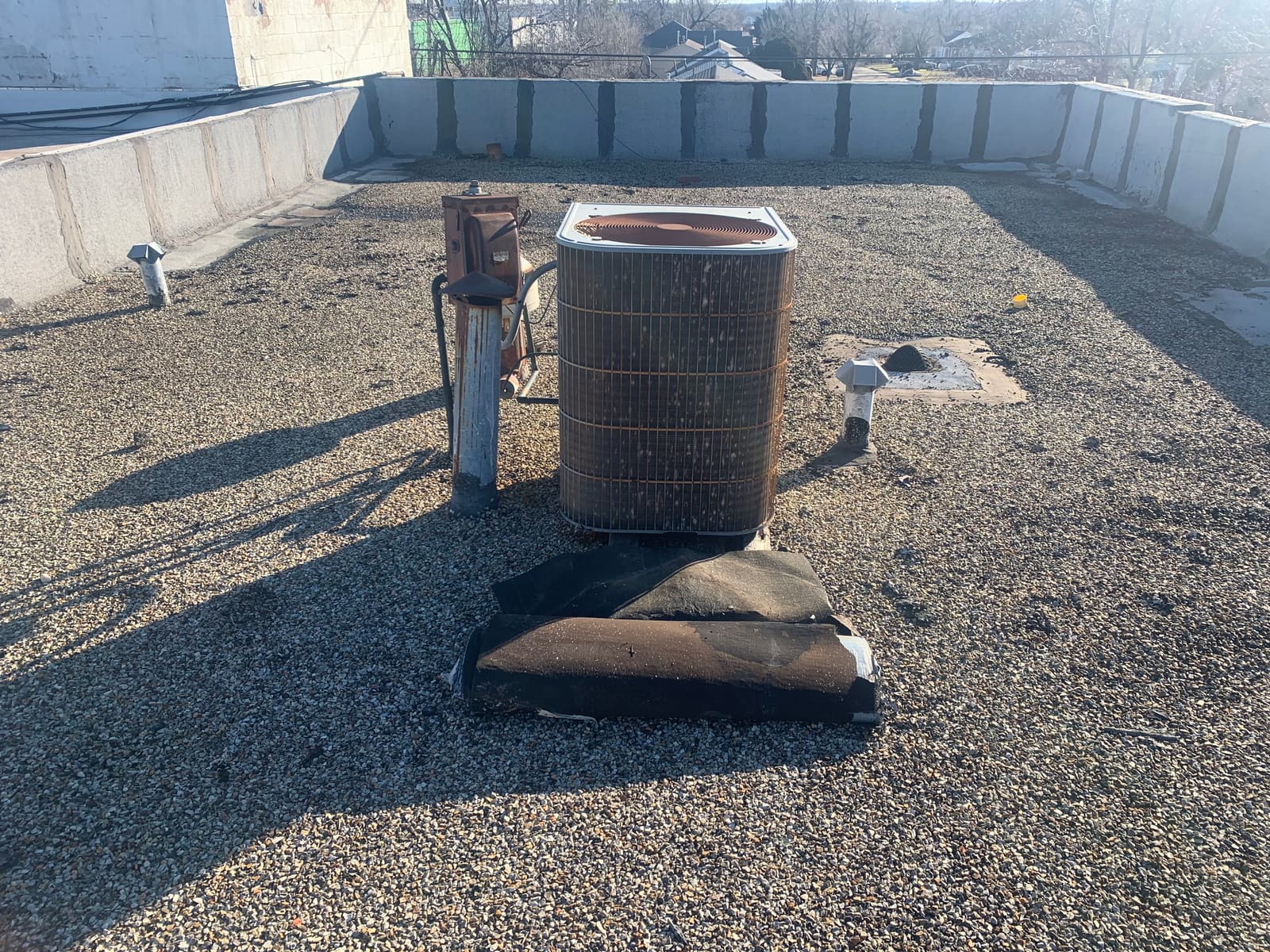 Commercial flat roof before work — aging ballast, a failing membrane and an HVAC unit