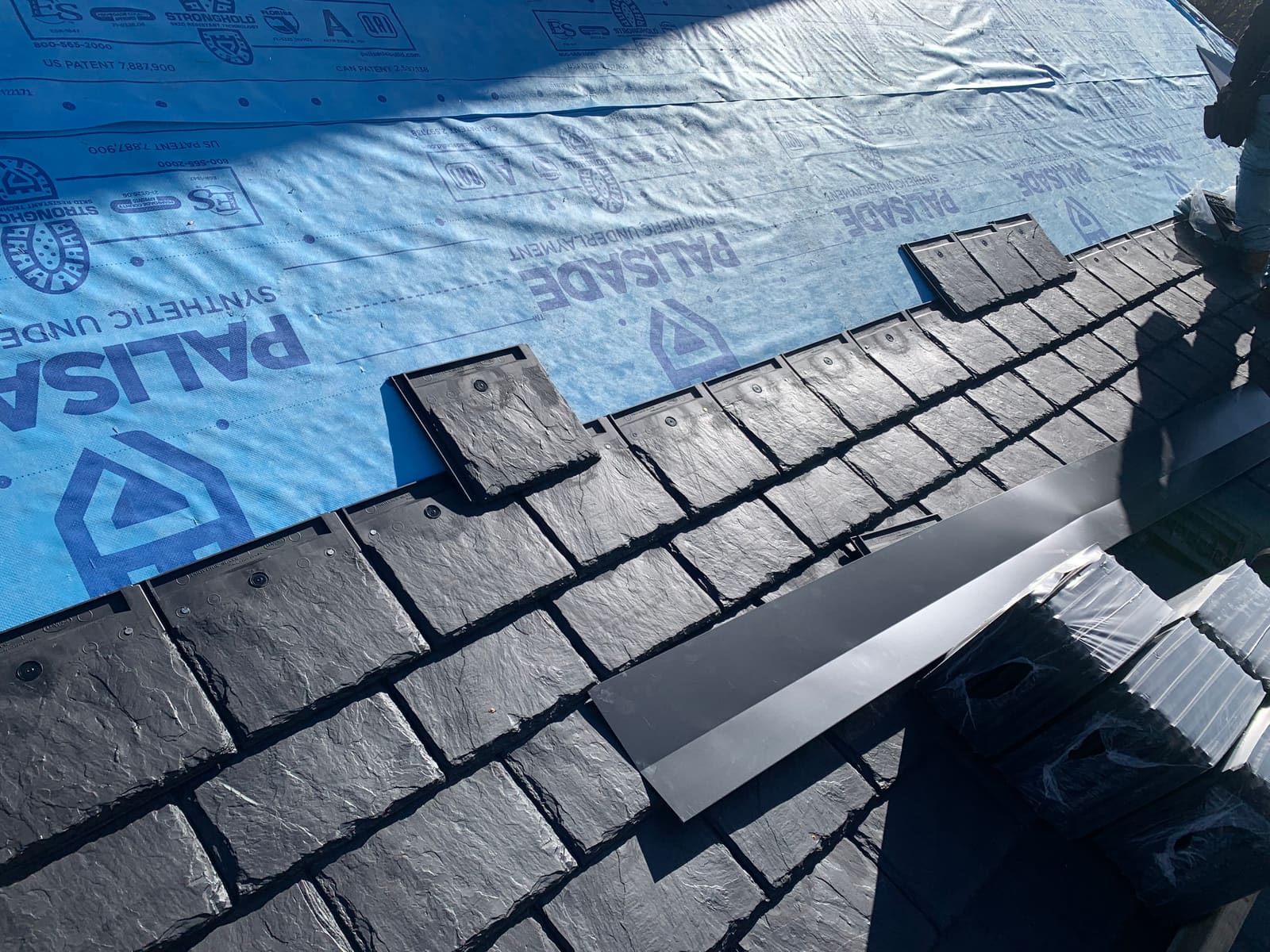 Synthetic slate going down course by course over synthetic underlayment