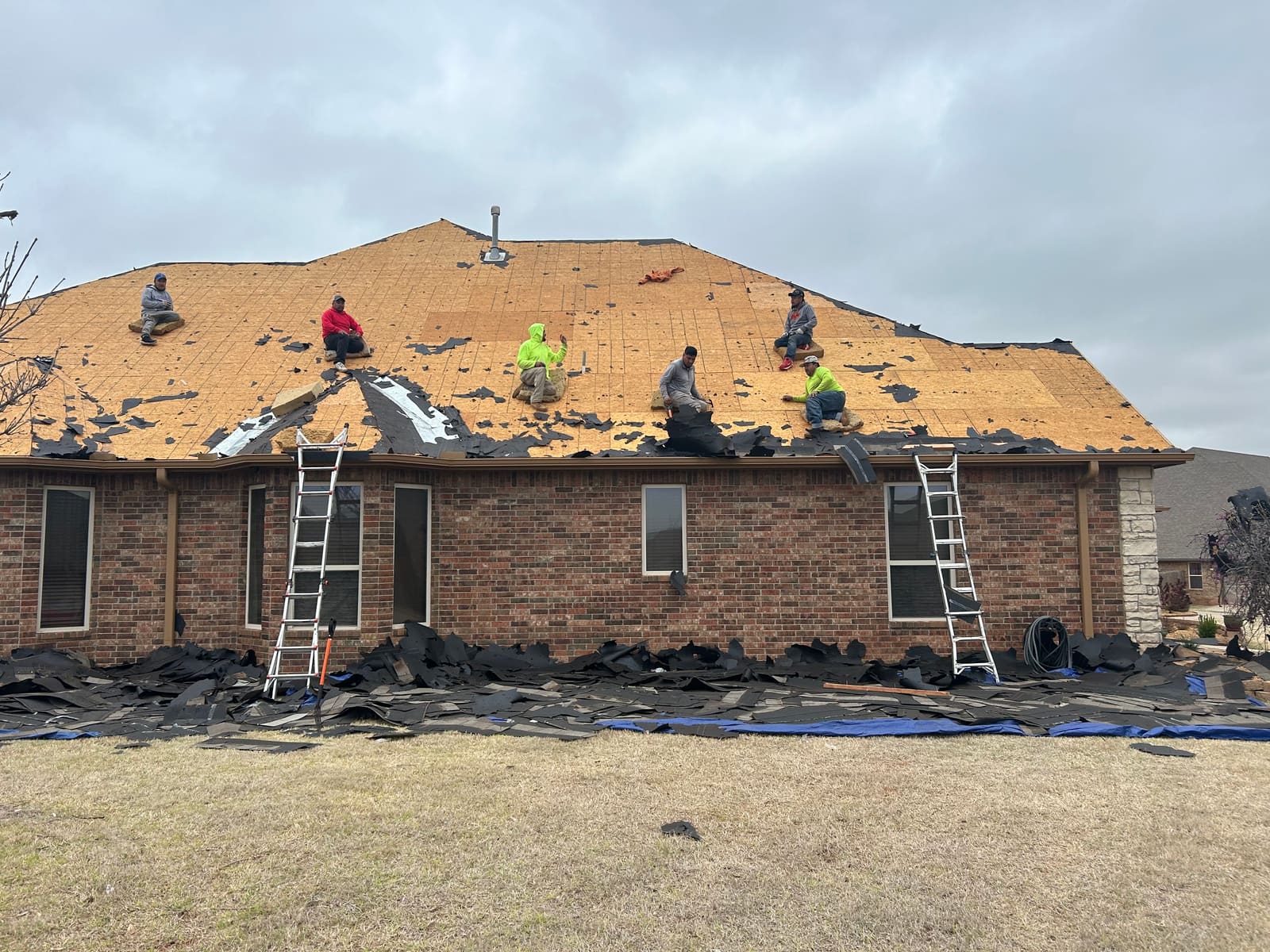 Full crew tear-off on a large hip roof after storm damage — six-man crew