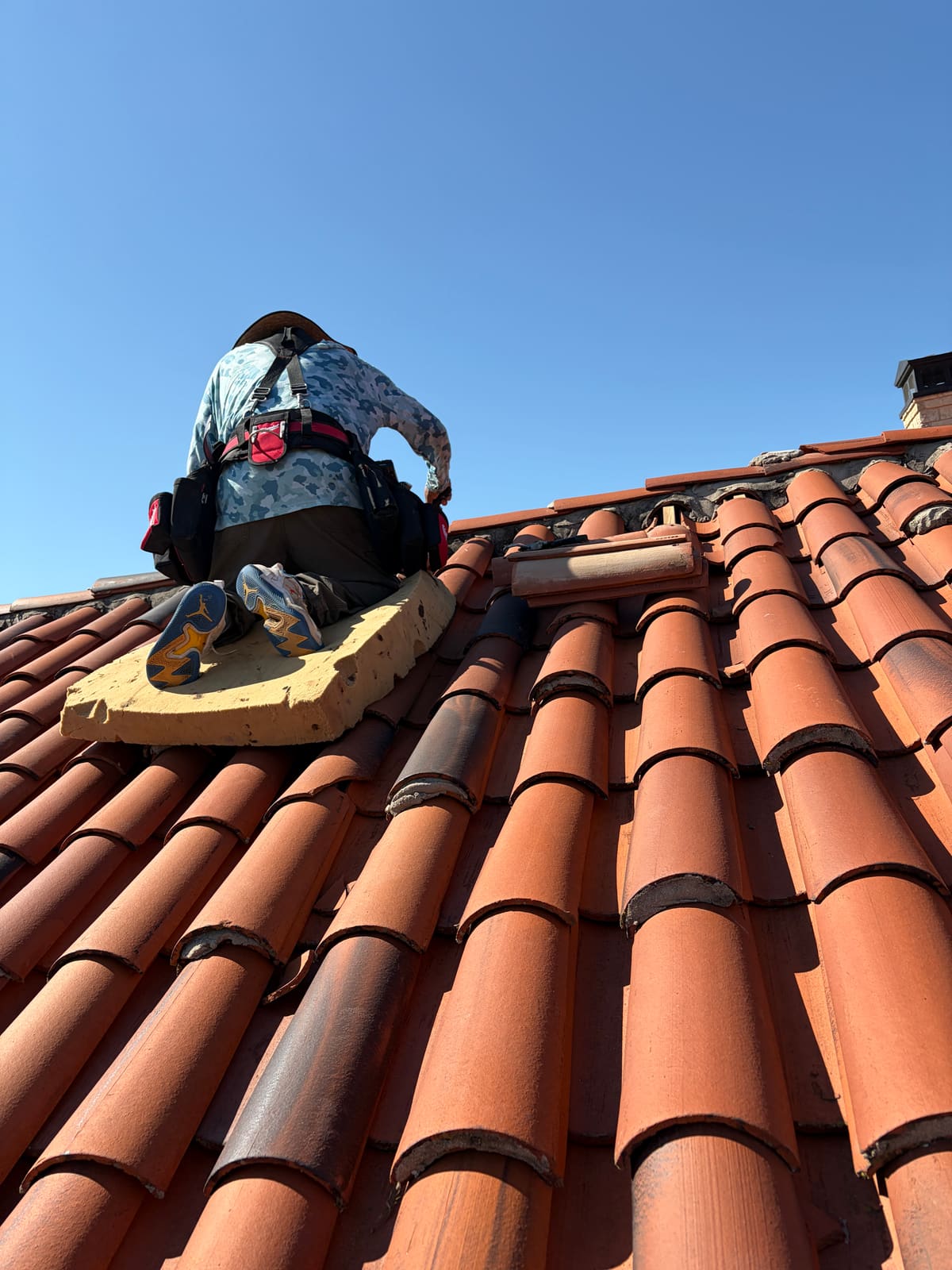 Barrel tile repair at the ridge — working close up on clay tile